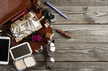  various necessary accessories in a women's handbag for urban life, flat lay on wooden background. free space for text.