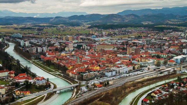 Celje, Slovenia. Car traffic in Celje, Slovenia. Bridge over the Savinja river. Aerial view of city historical center from the castle. Time-lapse during the cloudy day with mountains. Zoom out