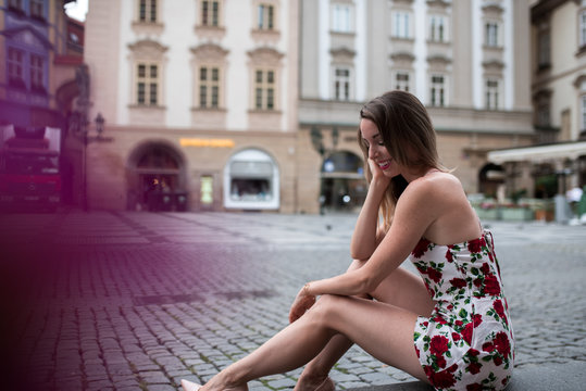 Woman sitting in a flower dress at old town square in prague, czech replic