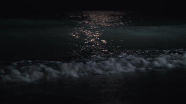 Slow motion shot of dark waves washing the seashore at night