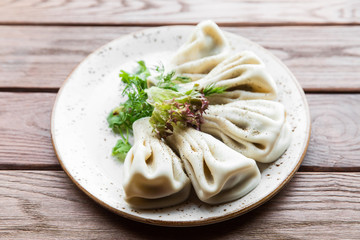 Georgian dumplings Khinkali with meat, greens on a wooden rustic table