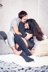 Happy Smiling Couple in love. Valentine's day. Winter portrait. Handsome young man and beautiful woman on a date spending time together at home scandinavian style.  Romance, family and love concept. 