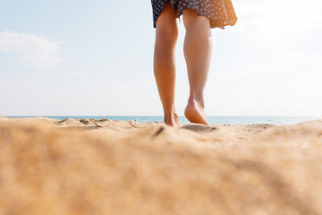 View of female legs walking on sand.