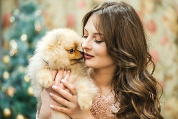 girl in dress with small dog at the Christmas tree