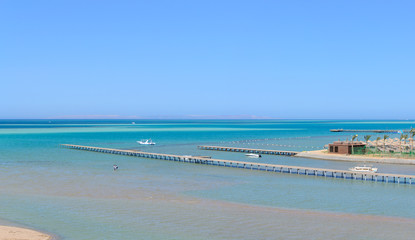 Beautiful paradise beach of the blue sea with a pier and a yacht panorama