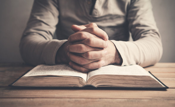 Man praying over a bible.