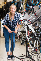Female master is using pump for bicycle in workplace