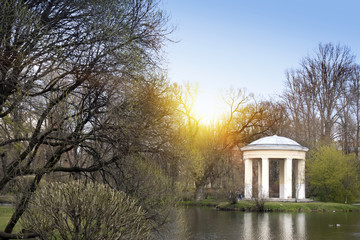 The pavilion on the bank of the lake in the spring park at the beginning of spring, without foliage...