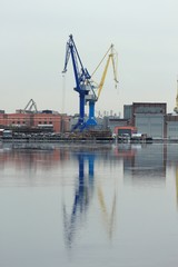 Port cranes on the shore with reflection in water