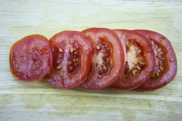 Sliced tomatoes laying on wooden desk. Red tomatos.