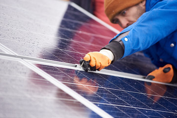 Selective focus on the hands of a professional male electrician installing solar panels working on...
