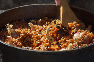 Preparation of pilaf on fire. Tourist bowler with food on bonfire, cooking in the hike, outdoor.