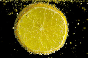 Lemon slice in mineral water on the black background.