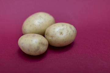 Pile of whole and raw potatos isolated against a red background