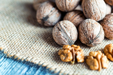 Walnuts and kernels on burlap on wooden backgound