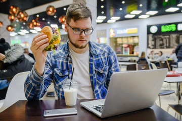 man works on laptop in cafe and it in same time