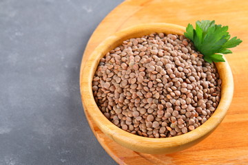 Red lentils in a wooden bowl on a wooden table.