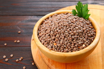 Red lentils in a wooden bowl on a wooden table.