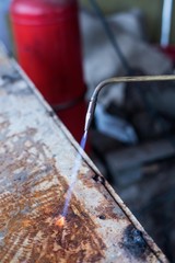 A man welds a metal with a gas burner