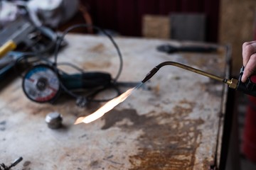 A man welds a metal with a gas burner