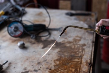 A man welds a metal with a gas burner