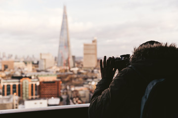 Fototapeta na wymiar Man taking photo with camera of modern London winter skyline