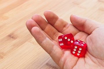 A hand holding red dice. This image can be used to represent gambling or risk taking. 