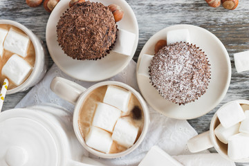 Cups with cacao and marshmallow, cupcakes and different decorations