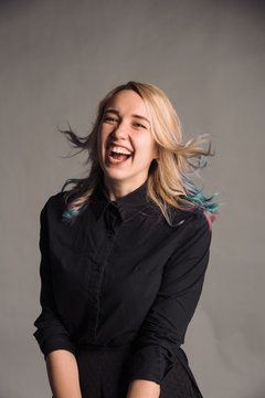 portrait of jumping young woman with colored hair in black shirt isolated on gray studio background posing to the camera