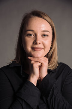 portrait of smiling young woman in black shirt isolated on gray studio background posing to the camera