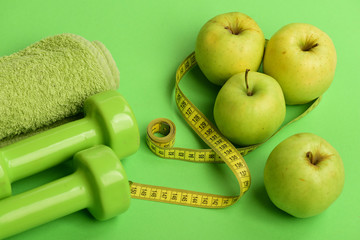 Barbells made of plastic near juicy green apples