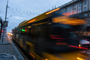 The motion of a blurred bus on the avenue at dusk.