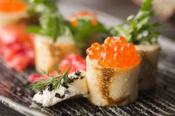 Pancakes with red caviar on the black dish. Russian Maslenitsa.