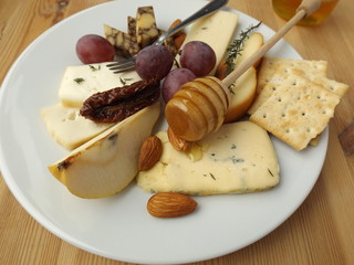 Cheese plate with fruits and nuts.  Cheddar sustained in porter, cheddar ordinary, Scamorza, Taleggio, cheese with blue mold.