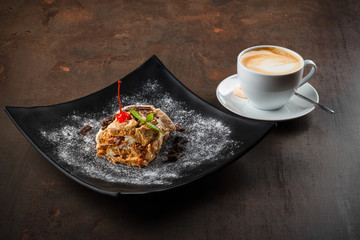 Dessert with a cherry on a dark background with a cup of coffee
