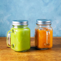 Freshly blended fruit smoothies of various colors and tastes in glass jars in rustic wooden tray. Yellow, green.