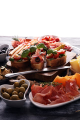 Italian antipasti wine snacks set. Cheese variety, Mediterranean olives, pickles, Prosciutto di Parma, tomatoes, artichokes and wine in glasses