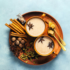 Masala tea chai latte traditional hot Indian teatime ceremony sweet milk with spices, herbs organic infusion healthy beverage in porcelain cup on blue table background