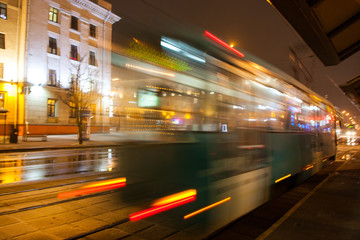 Fototapeta na wymiar The motion of a blurred tram on the street at dusk