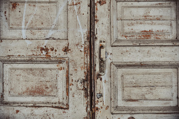 Metal handle on an old dilapidated wooden color creme  door