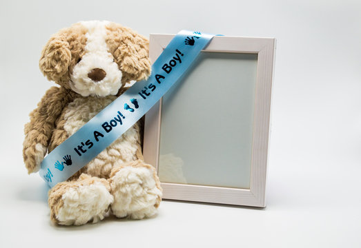 'It's A Boy' blue satin ribbon on stuffed teddy bear with empty picture frame to customize with photo