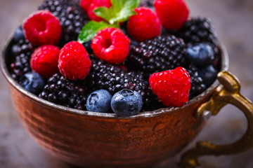 Berry Fresh in a copper cup on the Metal Background. Blackberries,Bramble,raspberry with mint.Food or Healthy diet concept.Super Food.Vegetarian.Copy space for Text.selective focus.