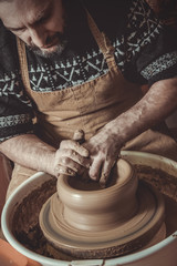 elderly man making pot using pottery wheel in studio