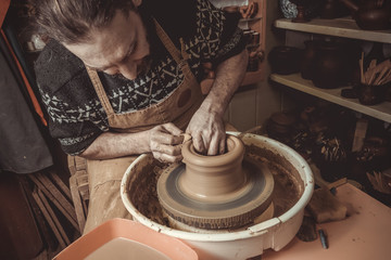 elderly man making pot using pottery wheel in studio