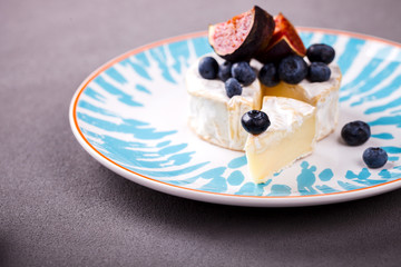 Cheese brie camembert on a plate.Snack with fresh figs, blueberries on a gray background.selective focus.