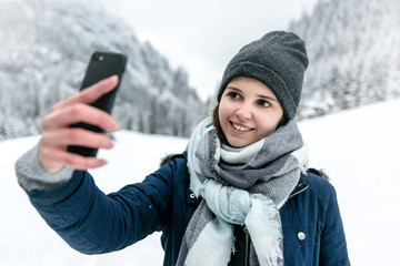 Uśmiechnięta dziewczyna robi sobie selfie w górach zimą. © Michał Magiera