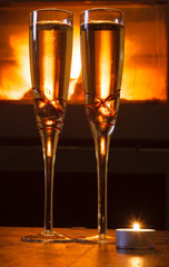 Two glasses of red wine in front of log fire