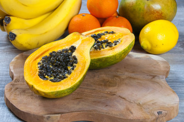 still life with banana, papaya, and oranges on wooden background