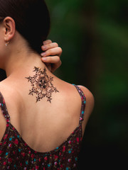 Mandala henna tattoo design on a back side of a neck. Beautiful indian mehendi ornaments painted on...