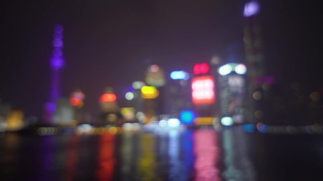 Abstract blurred background with skyscrapers of a big city and luminous advertising signs are reflected in the water